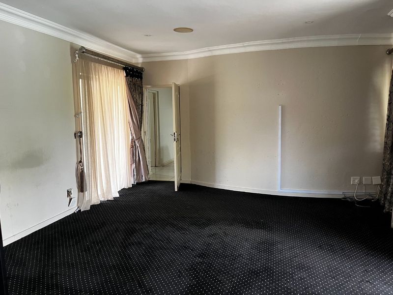 An empty living room featuring dark patterned carpeting, cove cornicing, and a sliding glass door providing access to the exterior.
