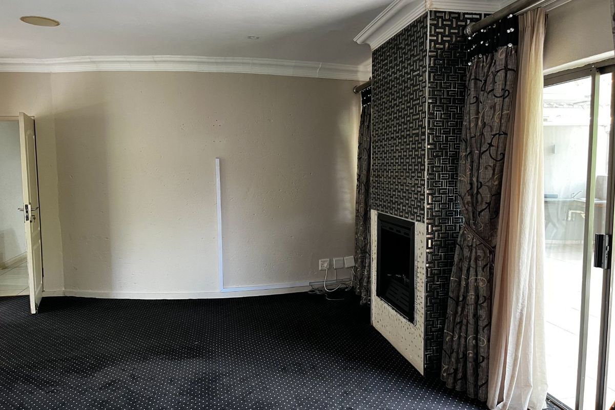 Spacious living room featuring a built-in fireplace with decorative tiling, crown molding, and direct access to an outdoor patio area through sliding glass doors.