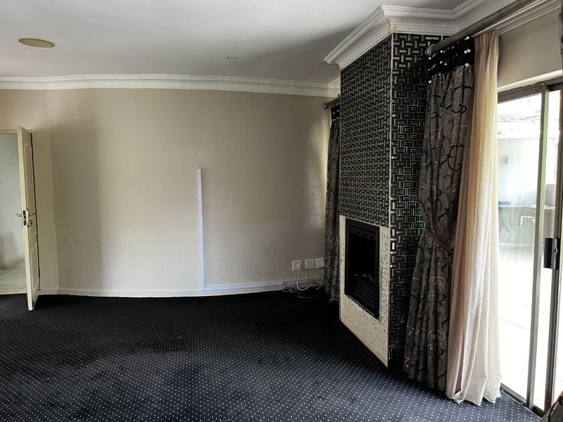 Spacious living room featuring a built-in fireplace with decorative tiling, crown molding, and direct access to an outdoor patio area through sliding glass doors.
