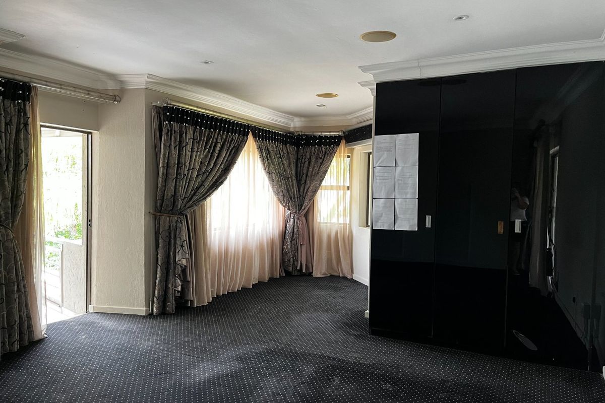 Spacious bedroom featuring dark fitted cupboards, recessed ceiling lighting, and direct access to an outdoor area through a sliding door.