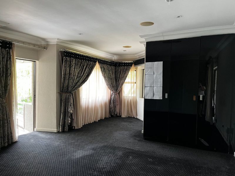 Spacious bedroom featuring dark fitted cupboards, recessed ceiling lighting, and direct access to an outdoor area through a sliding door.