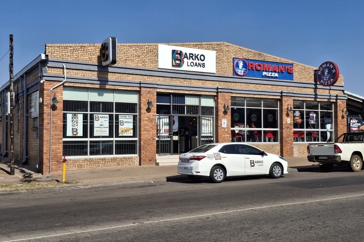 Front exterior view of a commercial building featuring face brick construction, large display windows, and prominent signage for multiple retail tenants.
