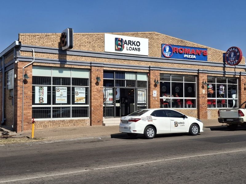 Front exterior view of a commercial building featuring face brick construction, large display windows, and prominent signage for multiple retail tenants.