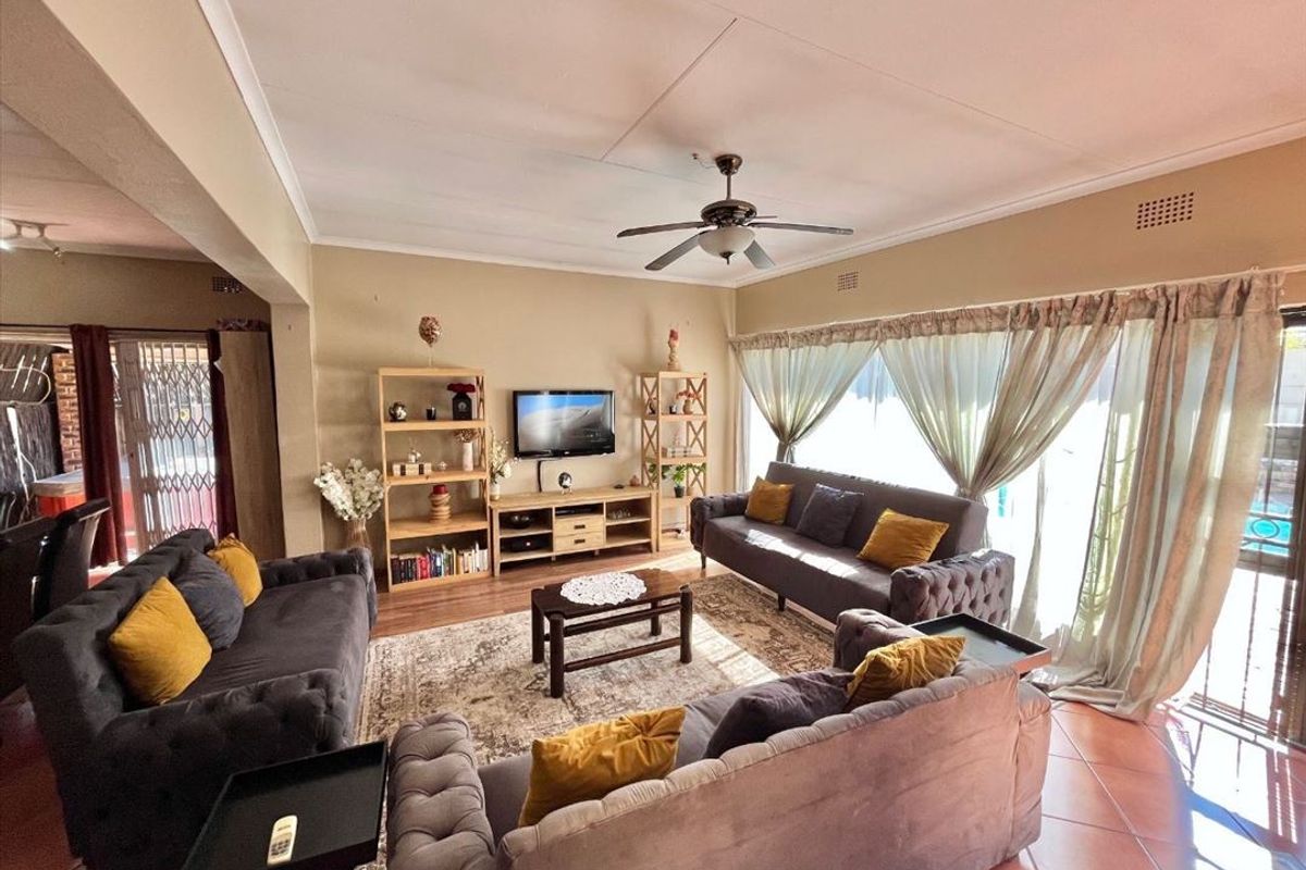 Spacious living room featuring tiled flooring, a ceiling fan, and large sliding glass doors providing natural light and access to the outdoor area.