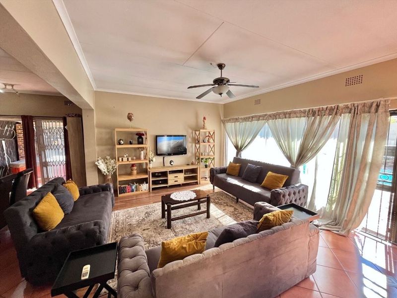Spacious living room featuring tiled flooring, a ceiling fan, and large sliding glass doors providing natural light and access to the outdoor area.