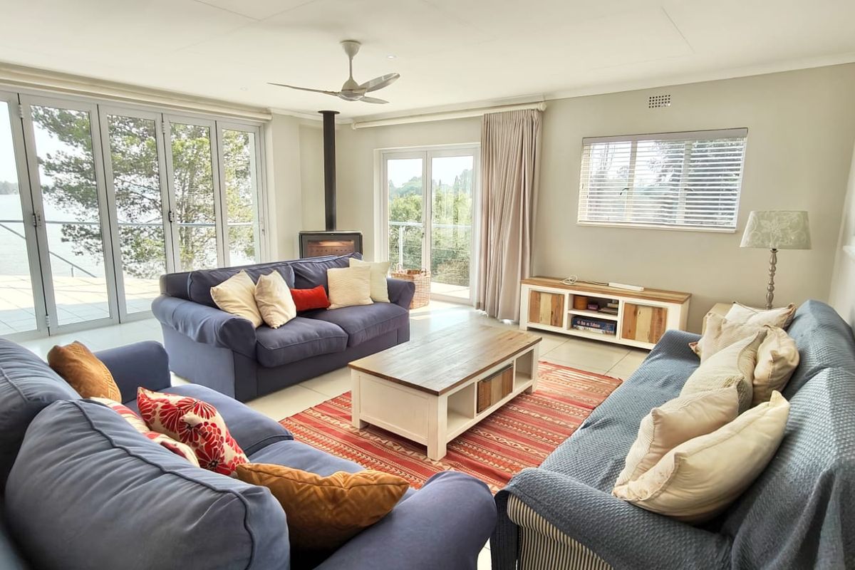 Bright and spacious living room featuring a modern freestanding fireplace, tiled flooring, and large aluminium stacker doors opening to a scenic outdoor view.