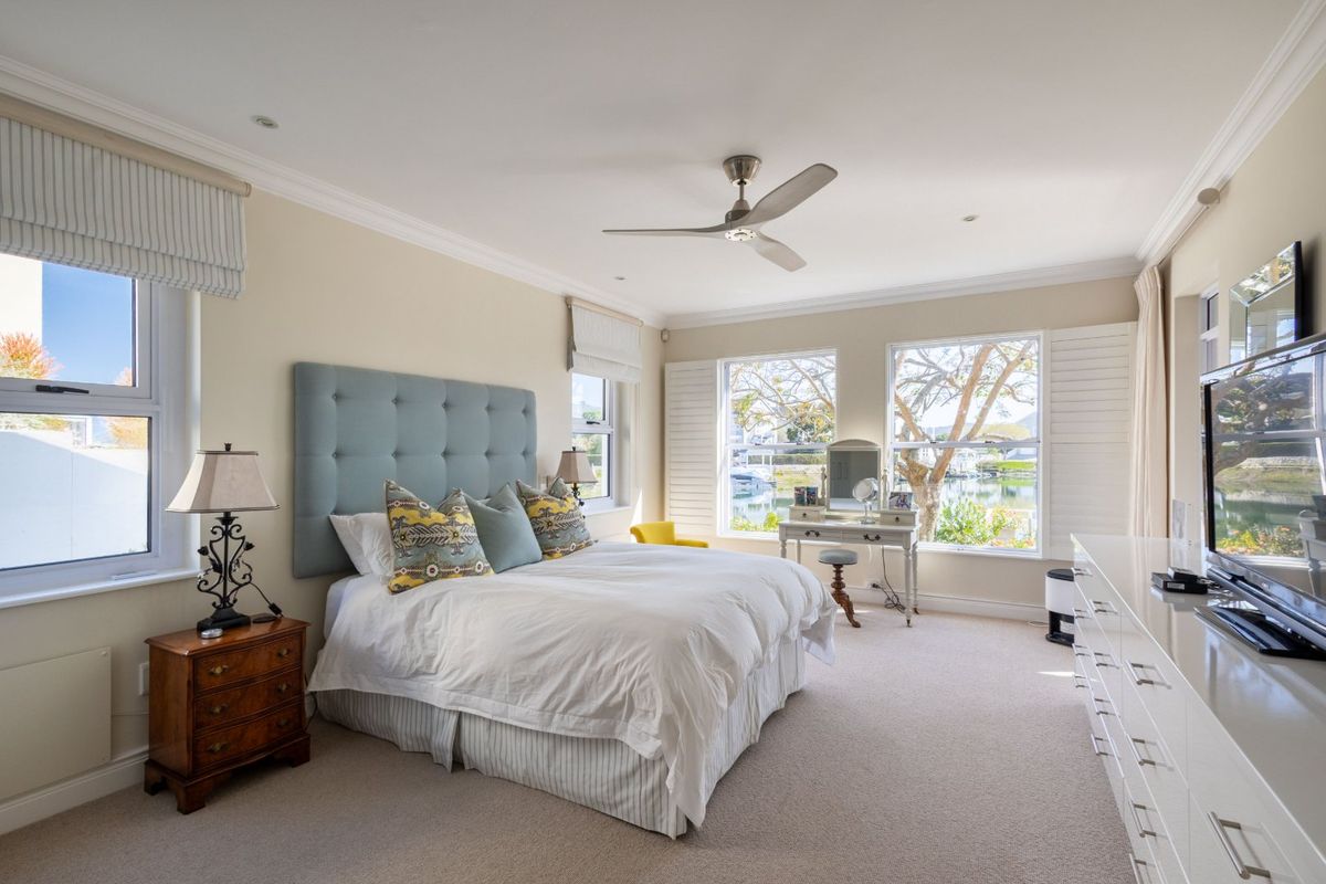 Spacious bedroom featuring neutral carpeting, crown molding, recessed lighting, a ceiling fan, and large windows with plantation shutters offering pleasant views.