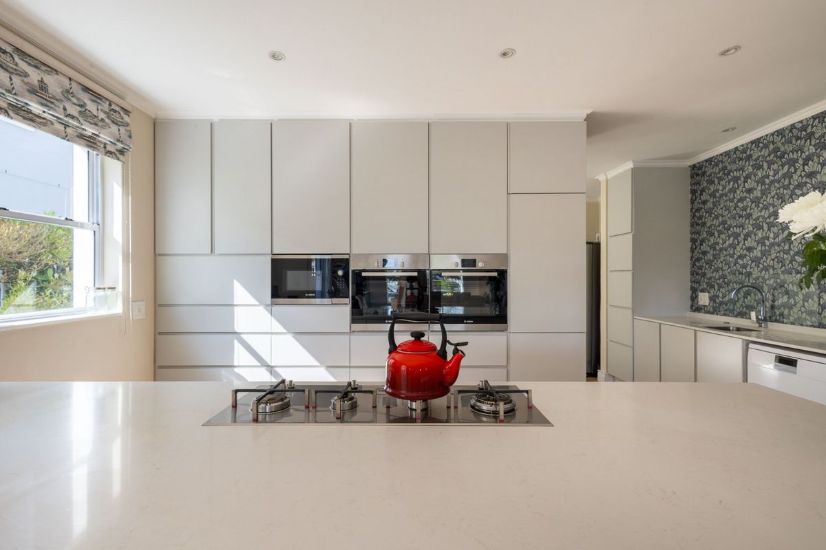 Modern kitchen featuring sleek integrated cabinetry, stone countertops, a central gas cooktop, and high-end built-in appliances in a bright, well-maintained space.