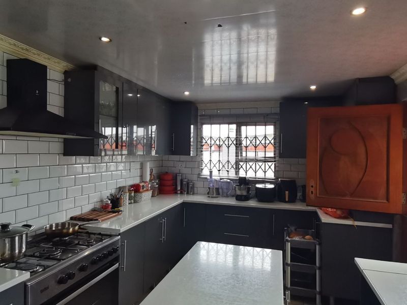 Modern kitchen featuring dark cabinetry, white subway tile backsplash, quartz countertops, and a gas stove with an integrated extractor fan.