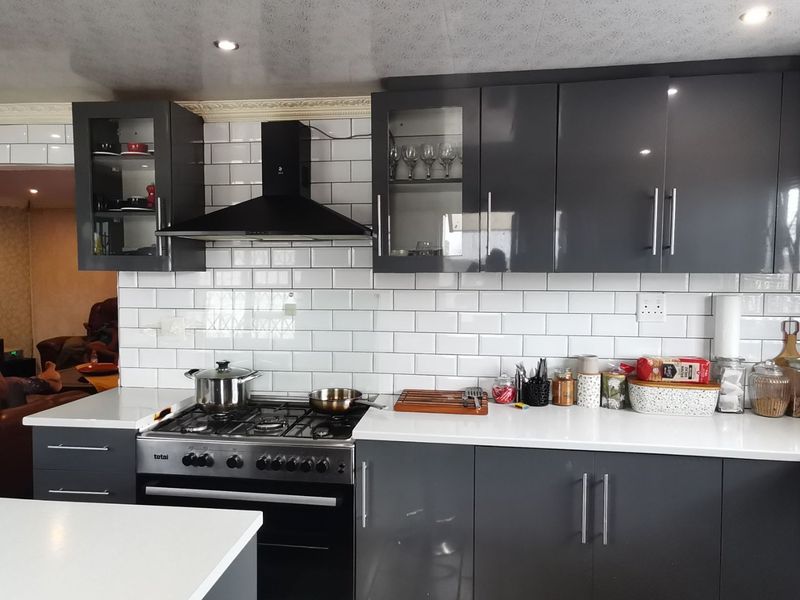 Modern kitchen featuring dark grey cabinetry, white quartz countertops, a subway tile backsplash, and a built-in gas stove with an extractor fan.
