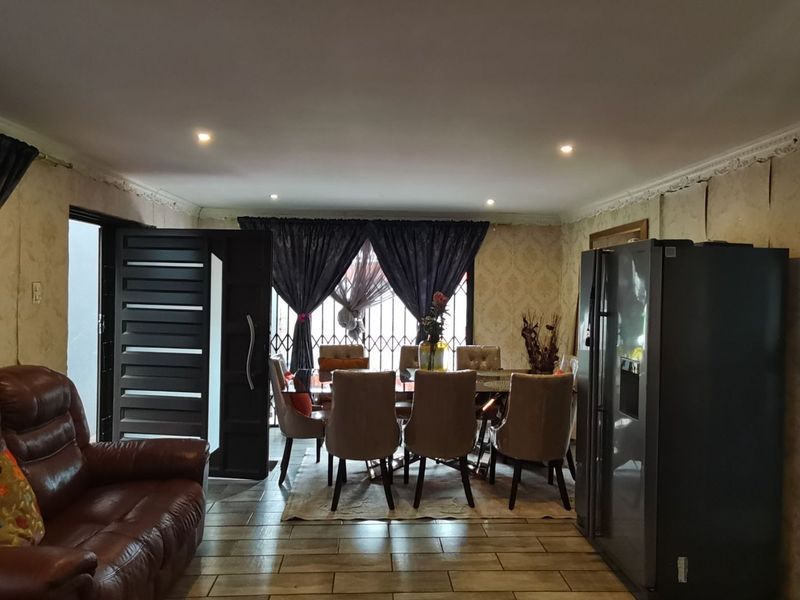 Open plan living and dining area featuring tiled floors, recessed lighting, and decorative cornicing, currently showing signs of wall finish deterioration.