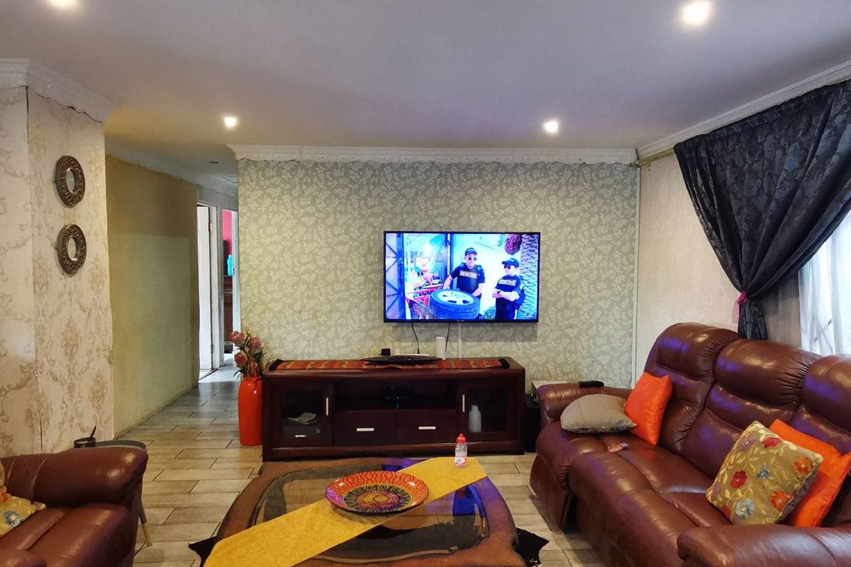 A living room featuring tiled flooring, recessed downlighting, and decorative wallpaper, providing a functional space for relaxation.