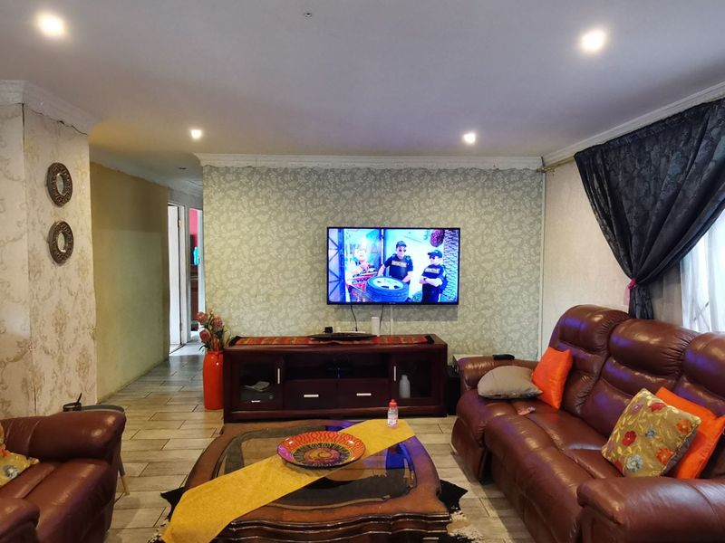 A living room featuring tiled flooring, recessed downlighting, and decorative wallpaper, providing a functional space for relaxation.