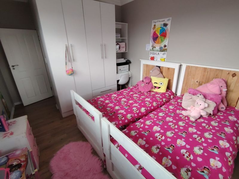 A well-maintained bedroom featuring laminate flooring, coving, and a functional built-in wardrobe with ample storage space.