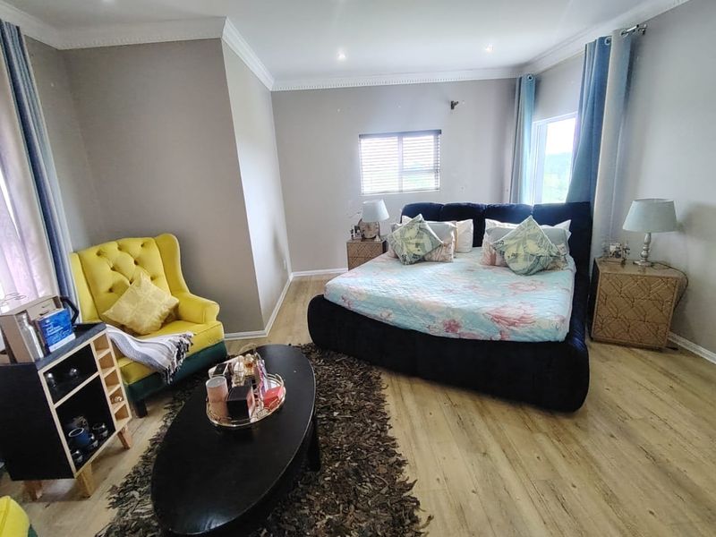 Spacious bedroom featuring light-toned laminate flooring, decorative ceiling cornicing, and recessed downlighting, creating a comfortable and well-maintained living space.