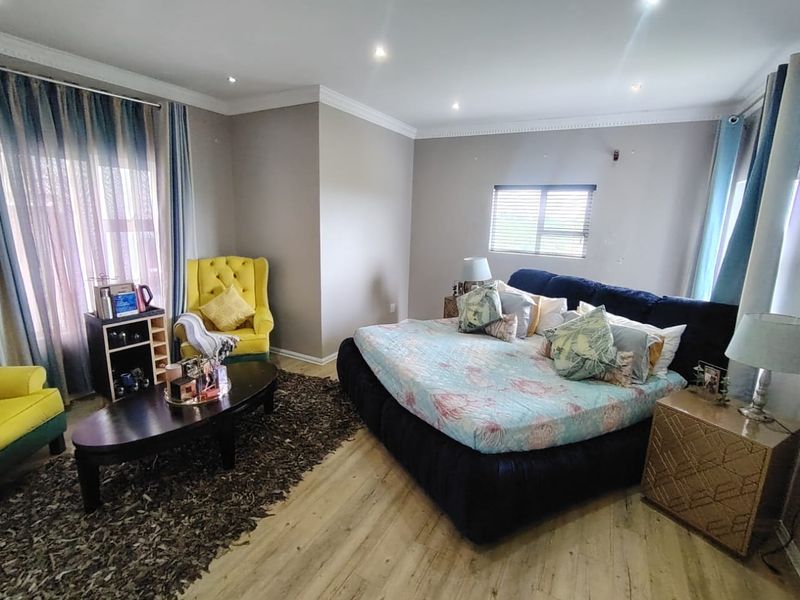 Spacious bedroom featuring laminate flooring, recessed downlighting, and coved ceiling details, providing a comfortable and well-maintained living space.