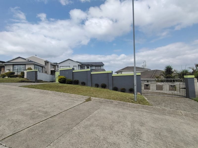 Street view of the property featuring a modern grey boundary wall with lime green accents and a secure metal sliding gate.