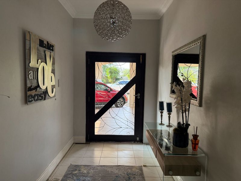 Welcoming entrance hall featuring tiled flooring, a decorative security door, and a modern pendant light fixture.