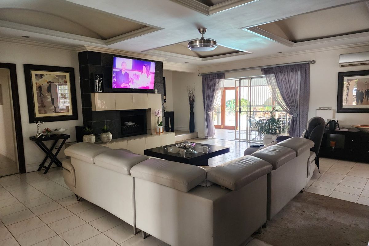 Spacious living room featuring a tray ceiling, tiled fireplace, and large sliding glass doors that provide natural light and access to the outdoor area.