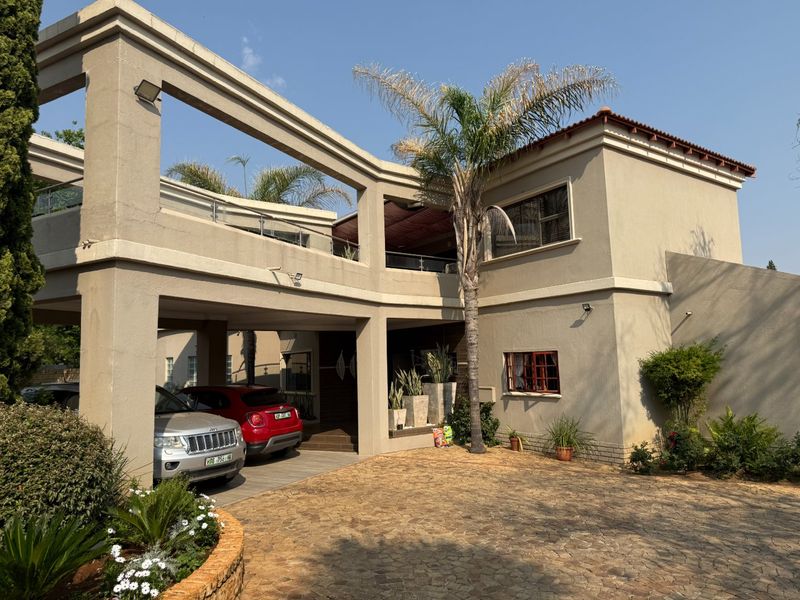 A double-story residential property featuring a paved driveway, integrated carport, and an upper-level balcony with modern architectural lines.