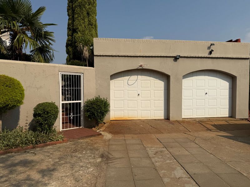 Front view of a double garage with a paved driveway and secure pedestrian gate access.