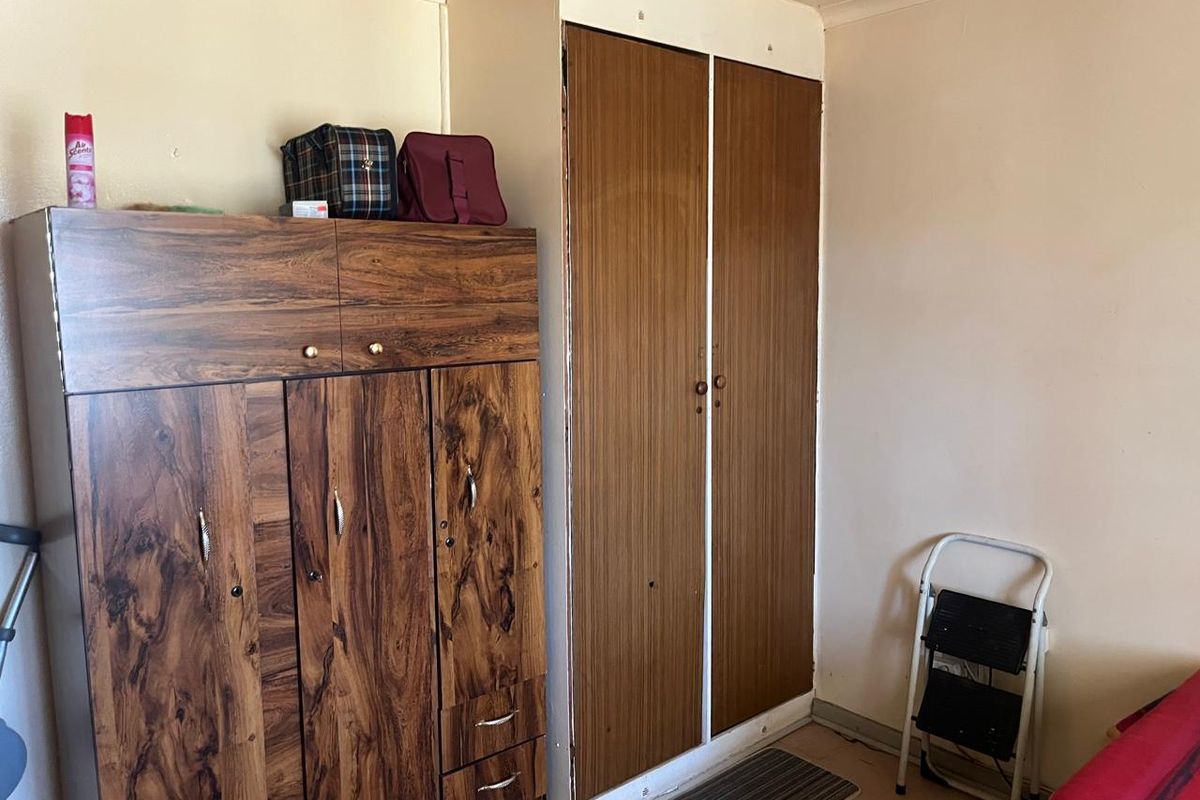 A bedroom featuring a built-in wardrobe with wood-grain finish and coving detail, requiring cosmetic updates to improve the overall aesthetic.