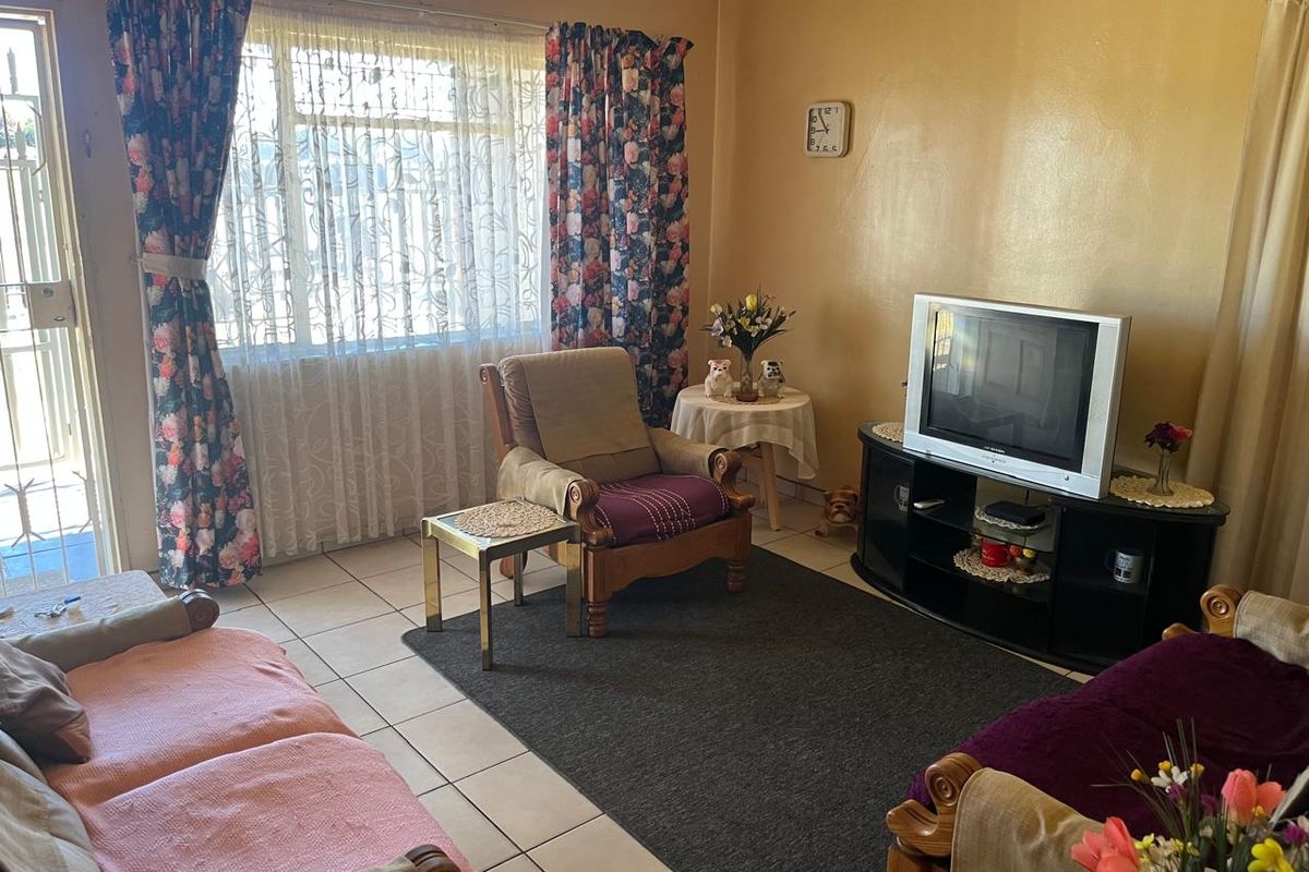 A living room featuring tiled flooring and a security gate, providing a functional and lived-in space.