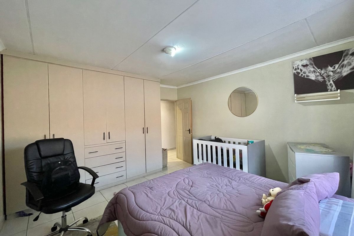 A functional bedroom featuring built-in cupboards, tiled flooring, and neutral wall finishes, providing a practical space for rest and storage.