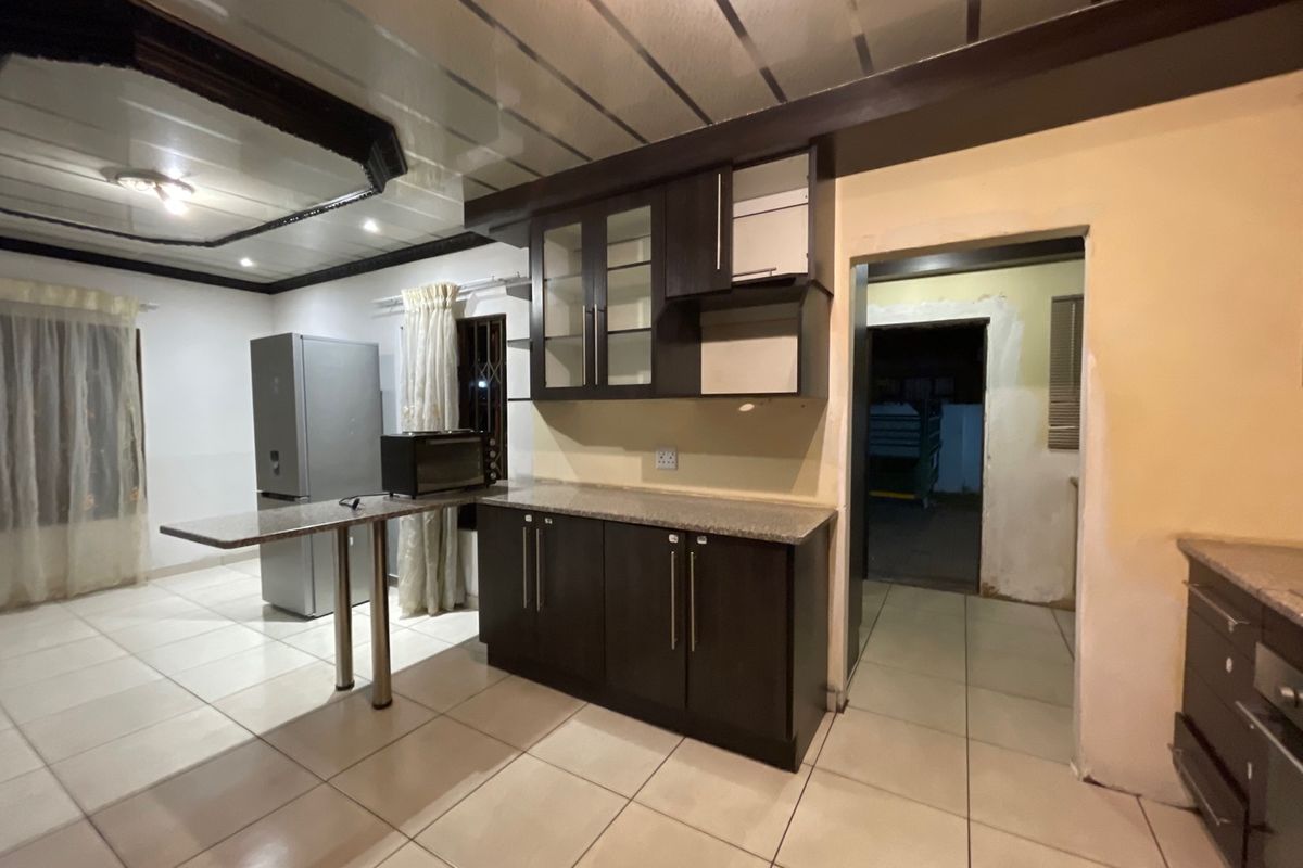 Kitchen area featuring dark cabinetry, granite countertops, and tiled flooring, requiring minor finishing work to complete the space.