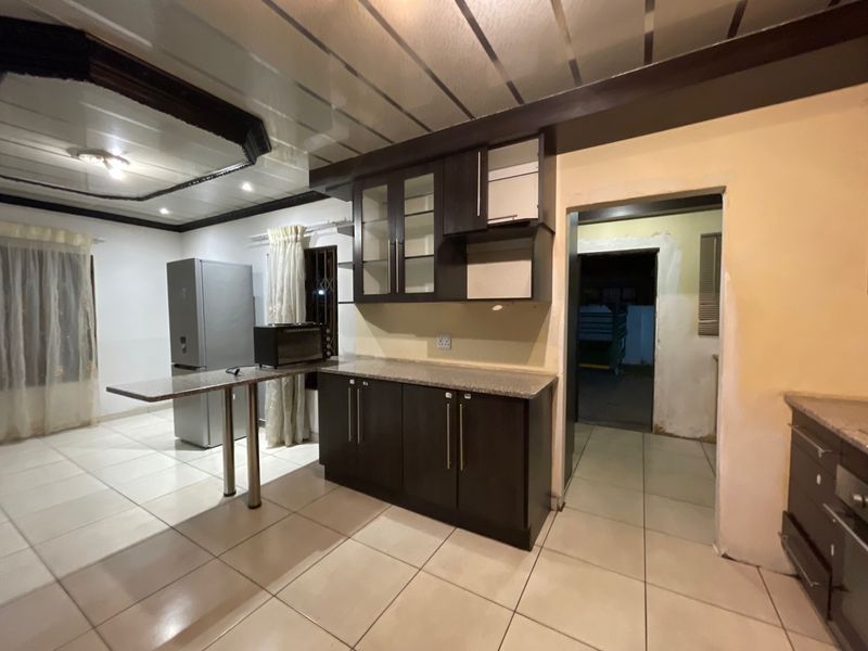 Kitchen area featuring dark cabinetry, granite countertops, and tiled flooring, requiring minor finishing work to complete the space.
