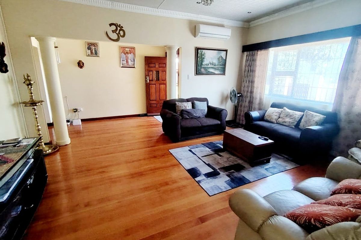 Spacious living room featuring warm laminate flooring, decorative columns, recessed lighting, and a wall-mounted air conditioning unit.
