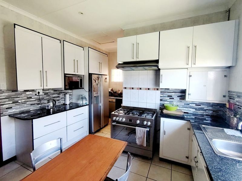 A functional kitchen featuring white cabinetry, granite countertops, a gas stove with extractor fan, and a modern tiled backsplash.
