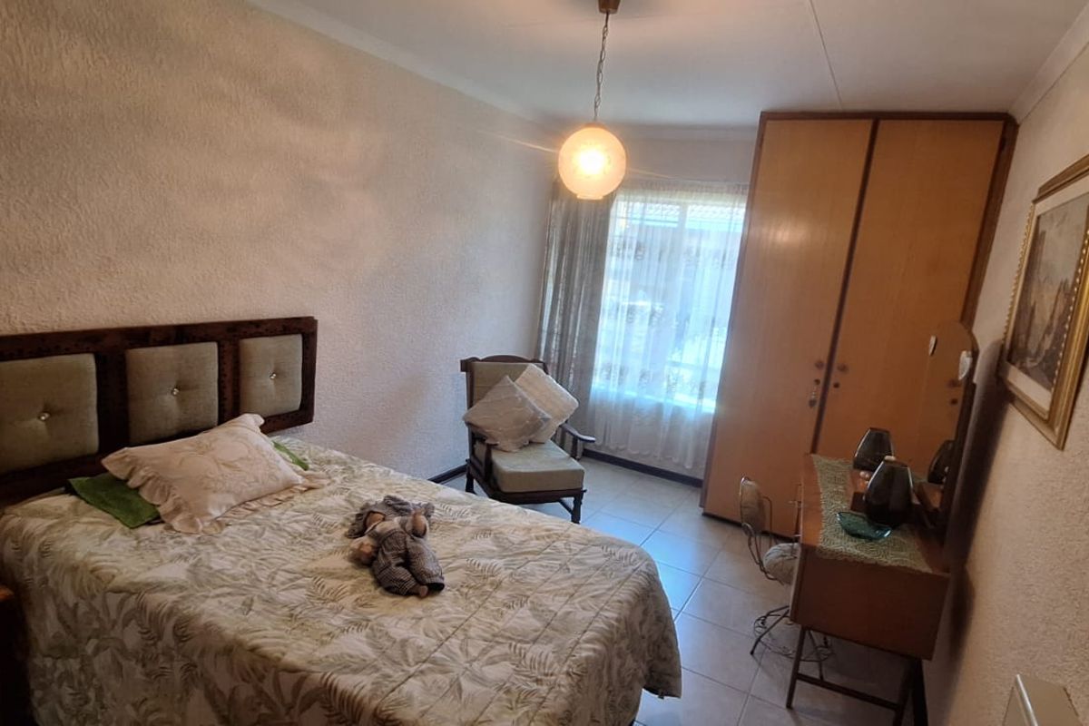 A functional bedroom featuring built-in wardrobe storage, tiled flooring, and textured wall finishes, offering a neutral base for potential updates.