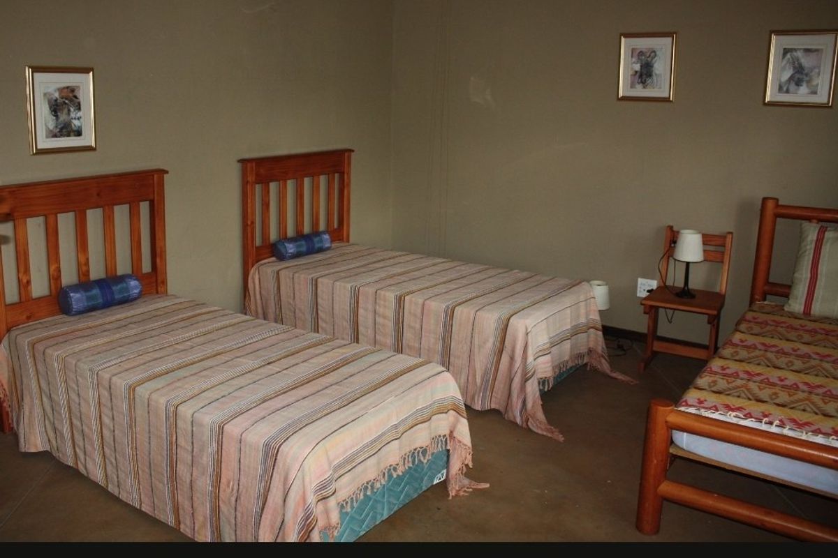A bedroom featuring a ceiling fan and neutral wall tones, currently configured with multiple beds.