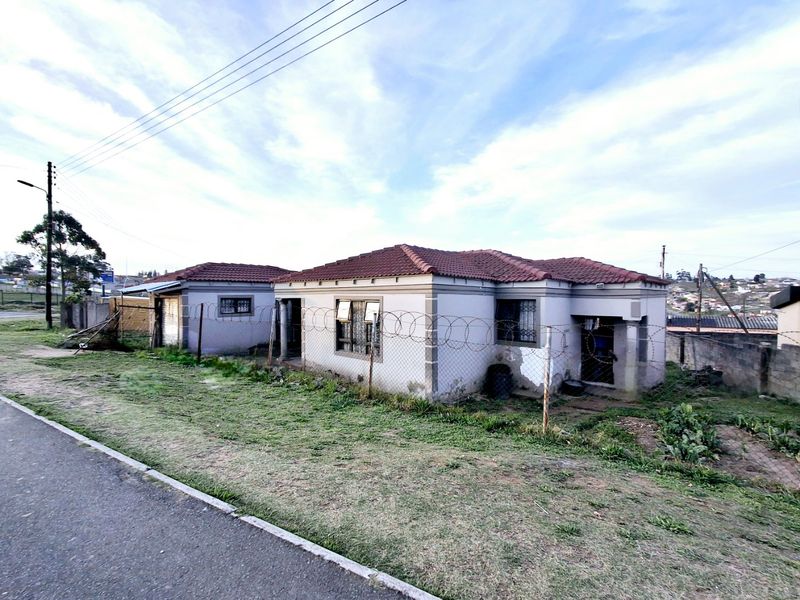 Front view of a detached house featuring a tiled roof, security fencing, and a paved driveway area.