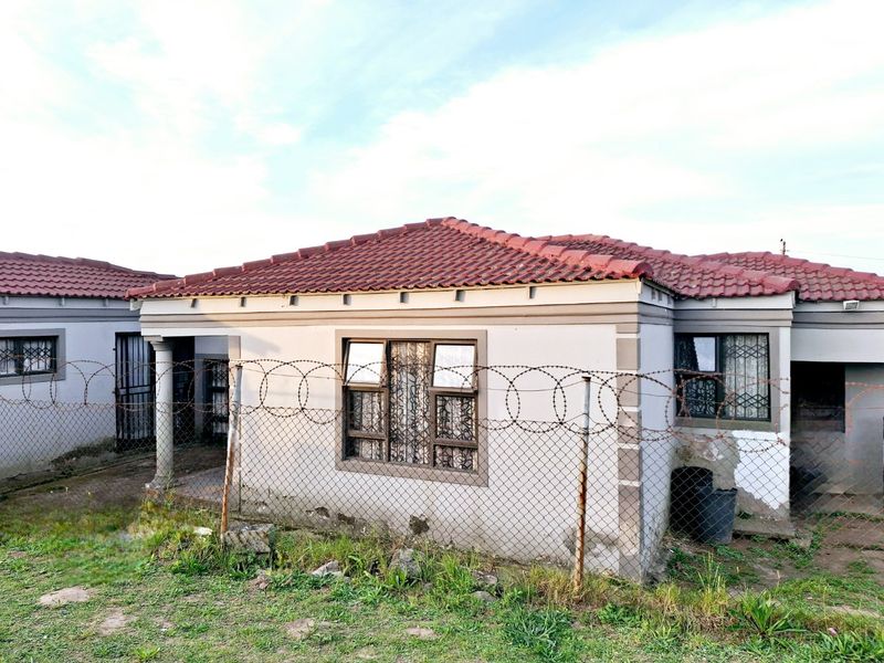 Front elevation of a single-story house featuring a tiled roof, security fencing with razor wire, and security bars on windows.