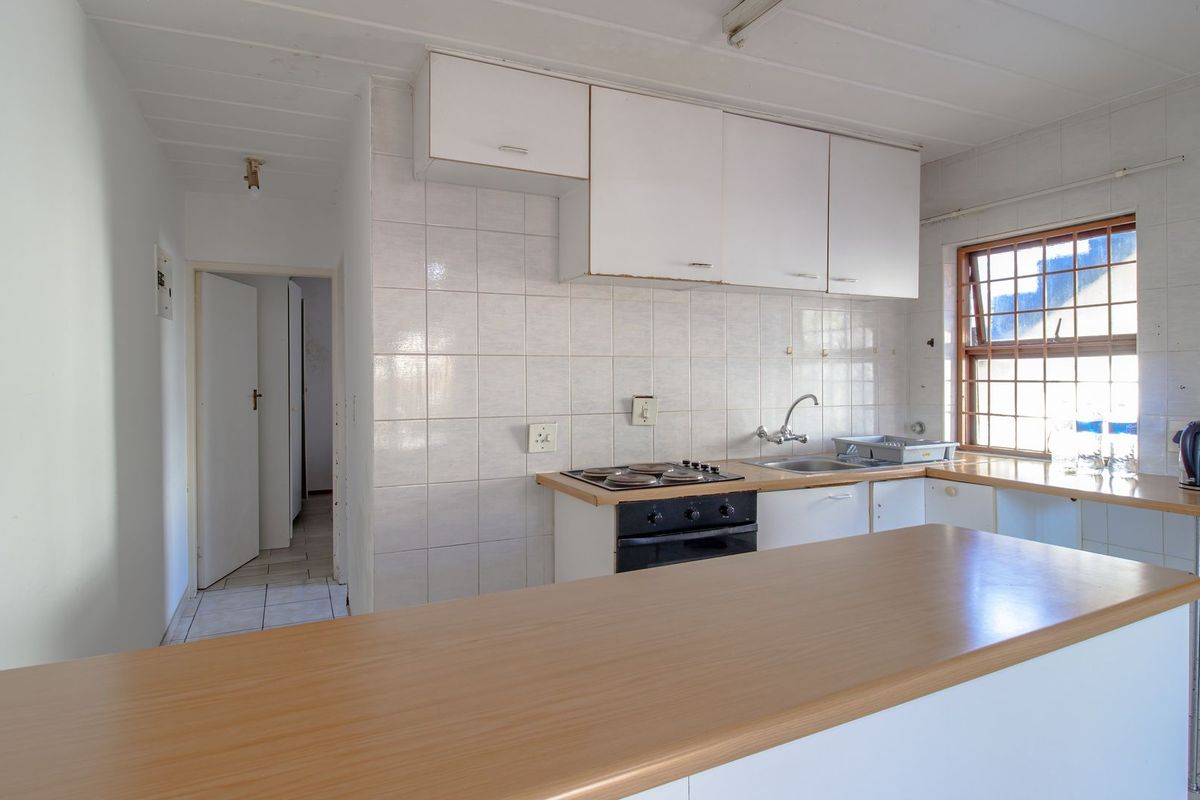 A functional kitchen featuring built-in cabinetry, a tiled backsplash, an integrated oven and hob, and a breakfast bar counter.