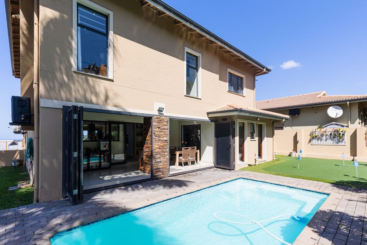 Rear exterior view featuring a swimming pool, paved patio area, and large stacking doors providing seamless indoor-outdoor flow to the main living space.