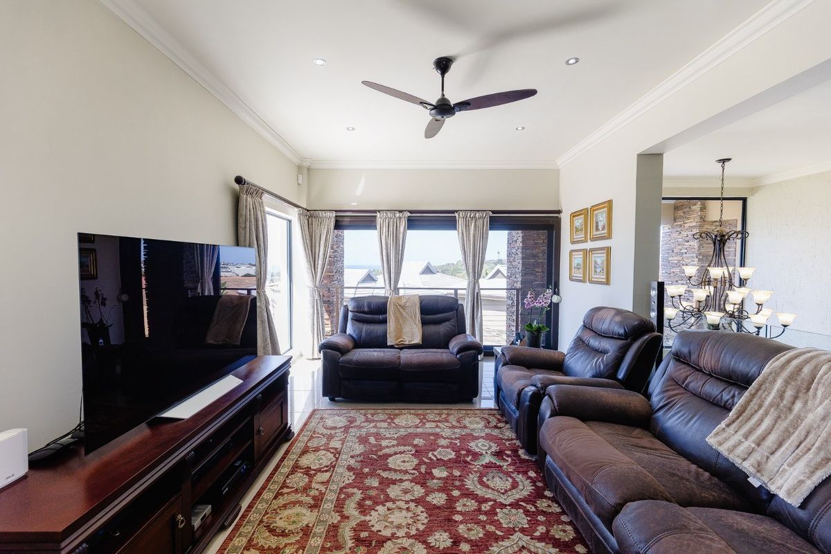 A well-maintained living room featuring tiled flooring, recessed lighting, a ceiling fan, and large sliding glass doors that open to an outdoor area.