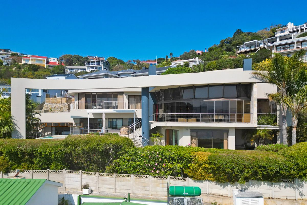 A modern multi-level residence featuring expansive glass facades, spacious balconies with stainless steel railings, and a well-maintained garden setting.