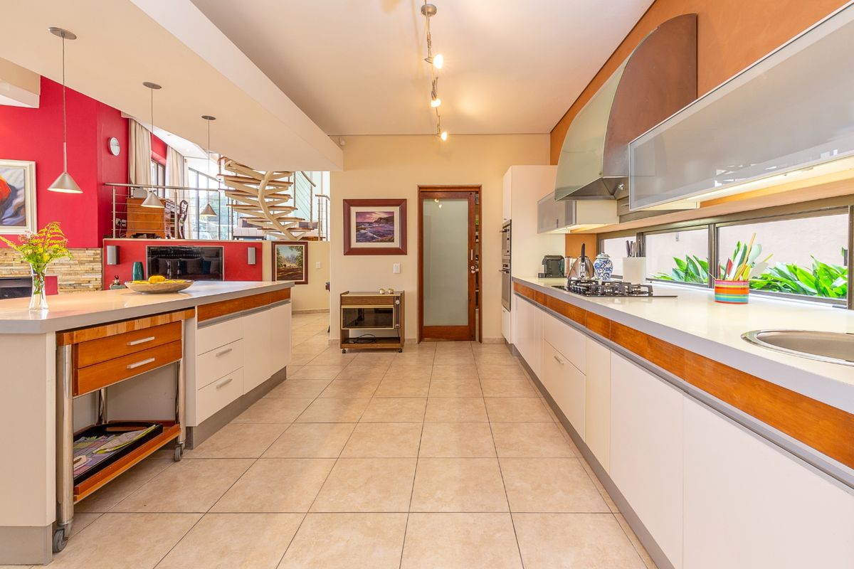 Spacious kitchen featuring a large island, modern cabinetry, gas hob, and integrated appliances, with an open-plan layout leading to a spiral staircase.