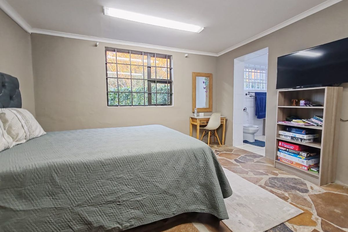 Spacious bedroom featuring unique flagstone flooring, a steel-framed window, and direct access to an en-suite bathroom.