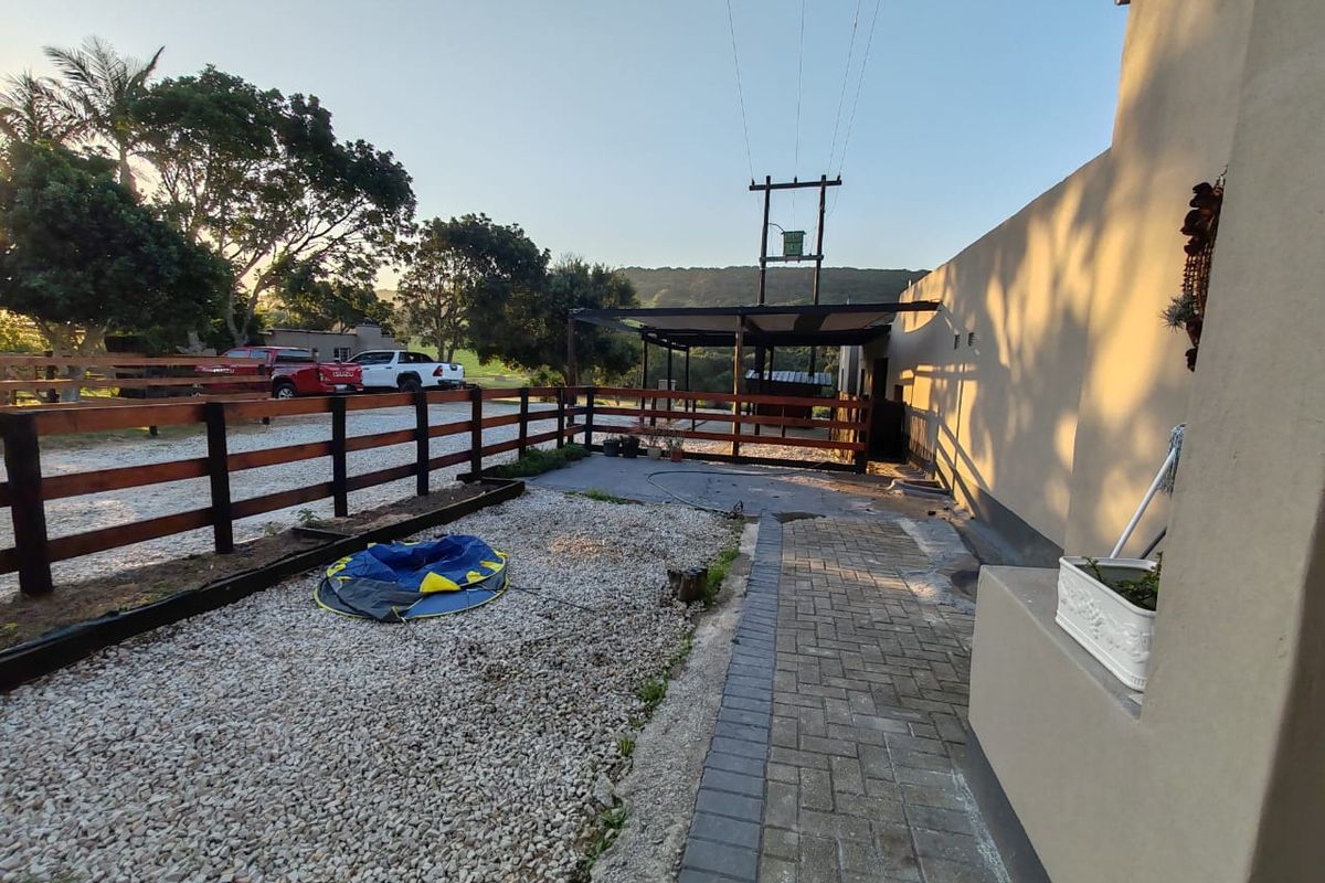 Rear exterior view of the property featuring a paved walkway, gravel garden area, and timber fencing with a covered outdoor structure.