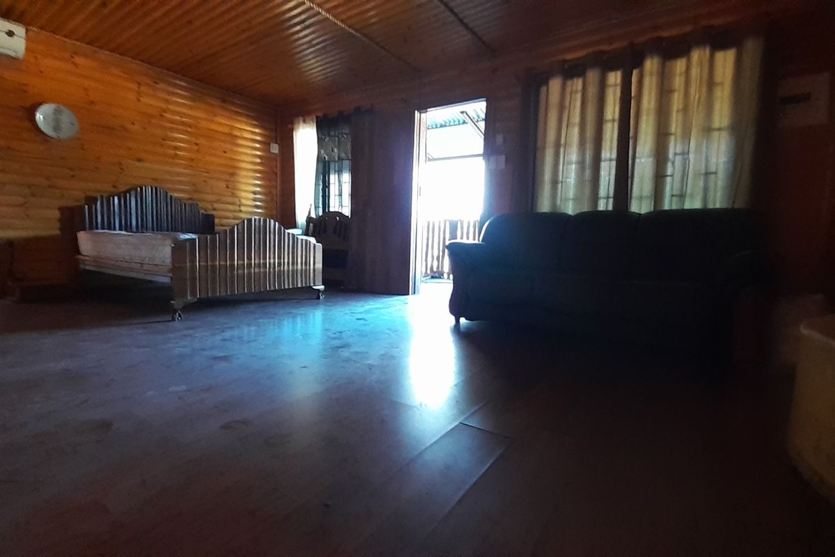 Spacious bedroom featuring warm timber wall cladding, ceiling, and flooring, equipped with a split system air conditioner and direct access to an outdoor area.