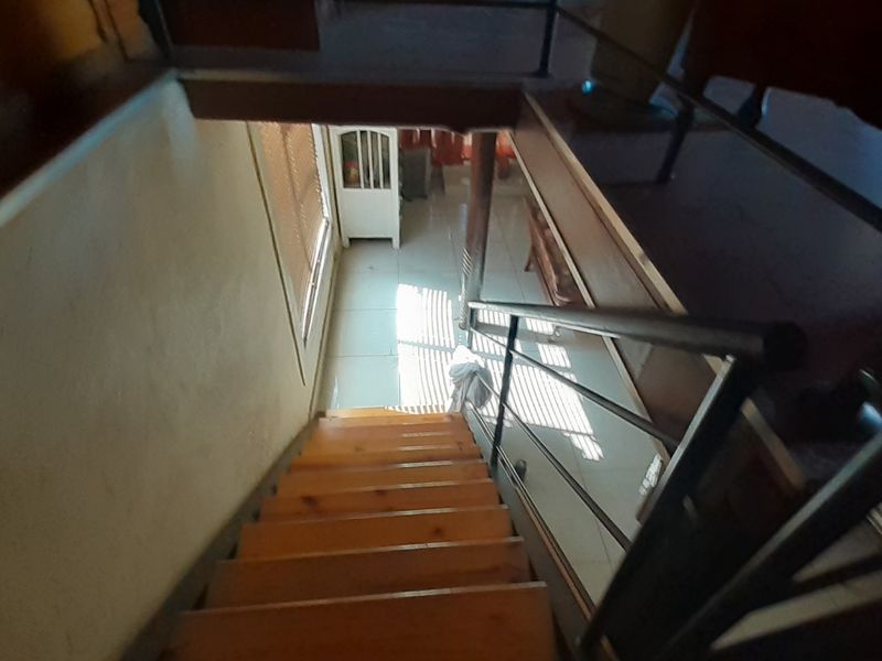 A view looking down a wooden staircase with a metal handrail, leading to a tiled lower level area.