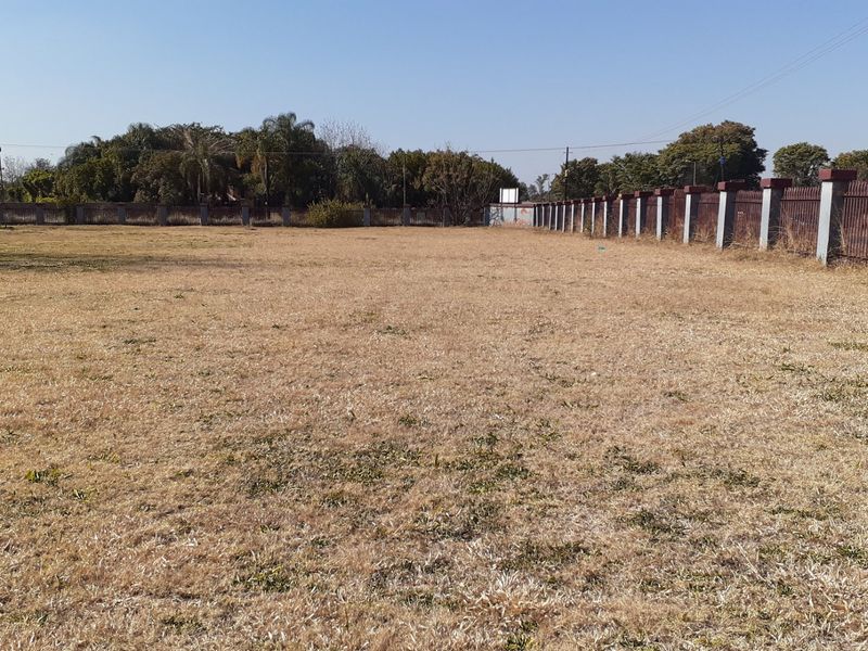 A large, open field area on the farm property featuring perimeter fencing and a raised water storage tank.