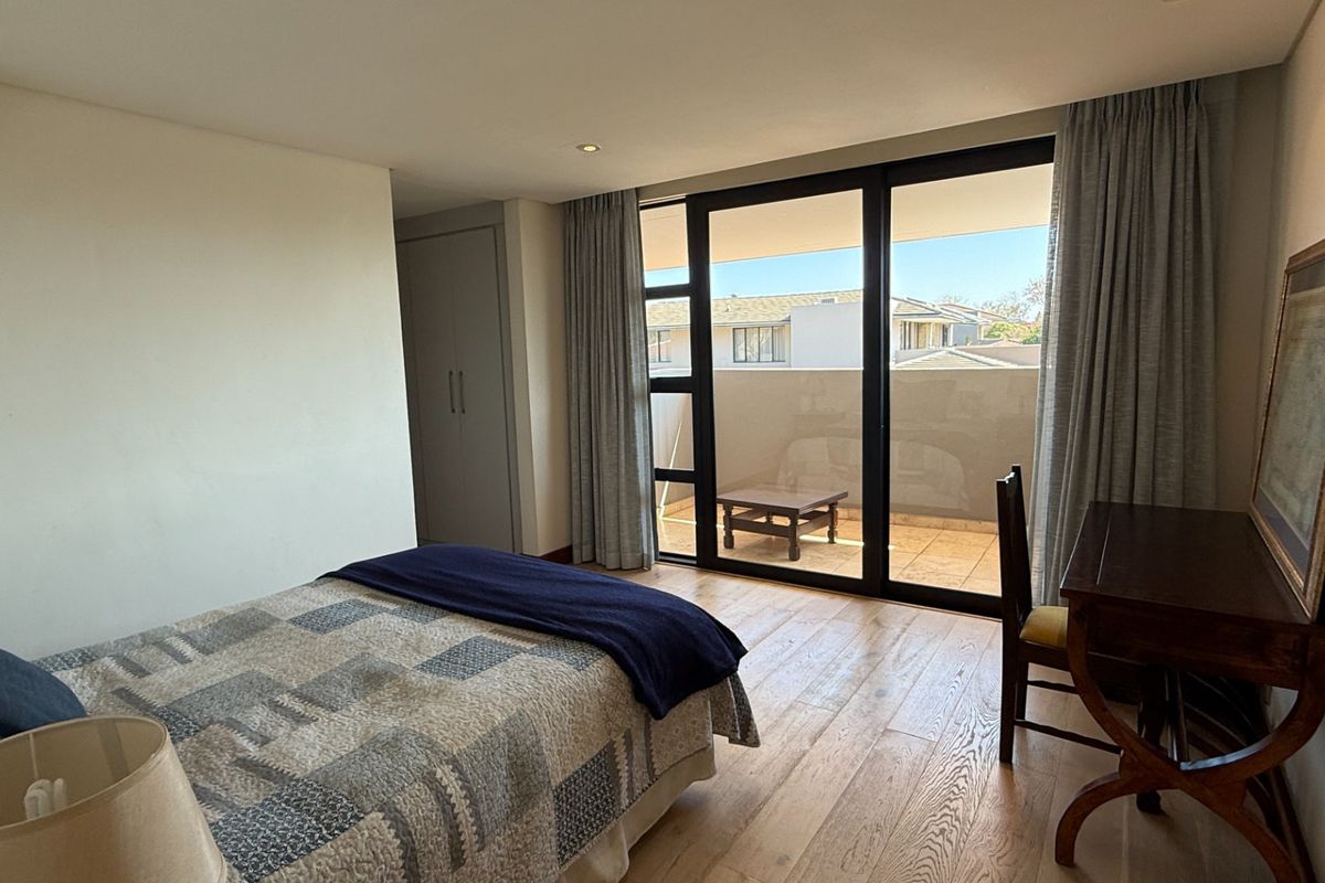 Spacious bedroom featuring hardwood flooring, built-in cupboards, and large sliding glass doors providing access to a private balcony.