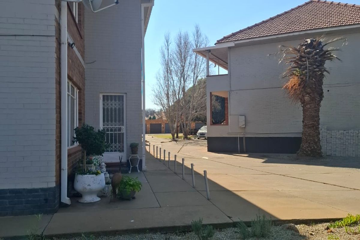 A view of the rear exterior of the apartment complex, featuring a concrete driveway, paved walkway, and brick building facades.
