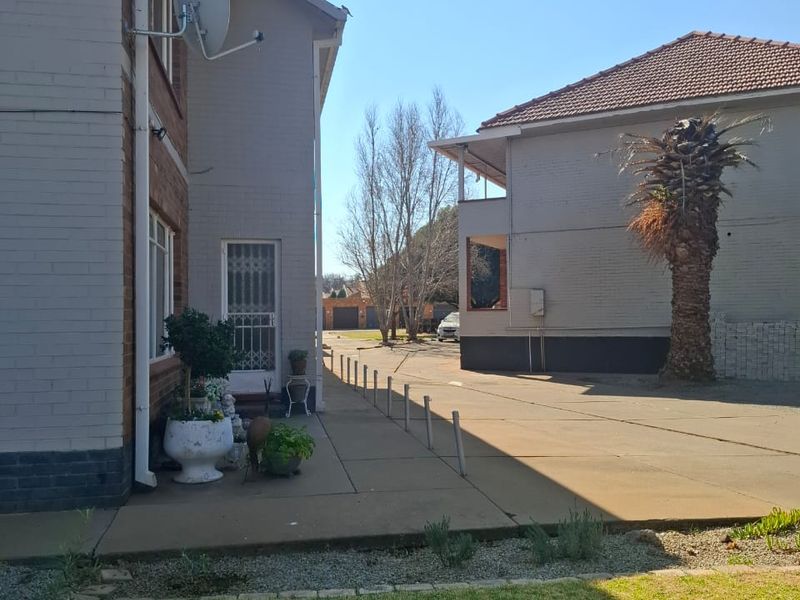 A view of the rear exterior of the apartment complex, featuring a concrete driveway, paved walkway, and brick building facades.