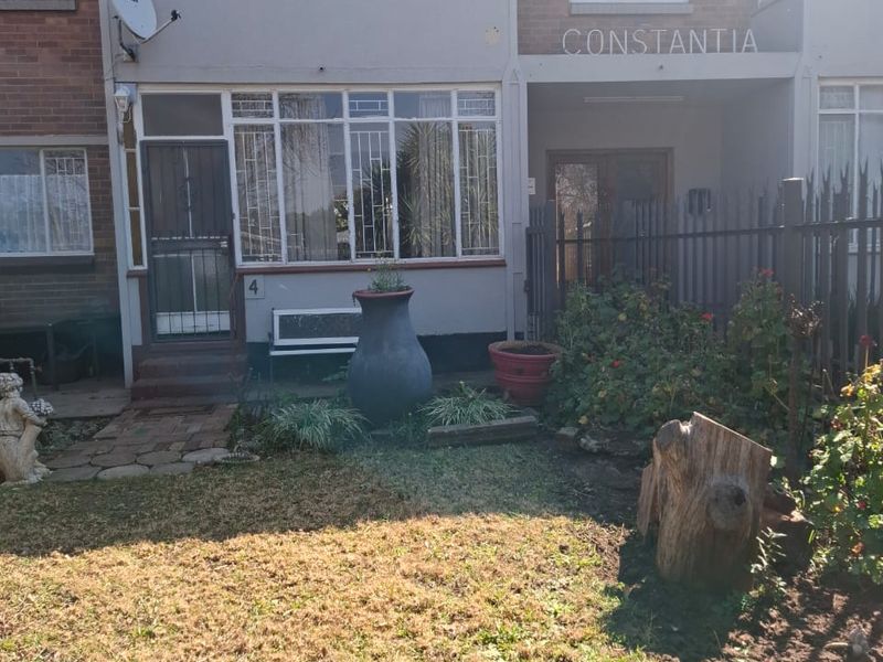 Front elevation of the Constantia apartment unit featuring an enclosed balcony, security gates, and a small private garden area.